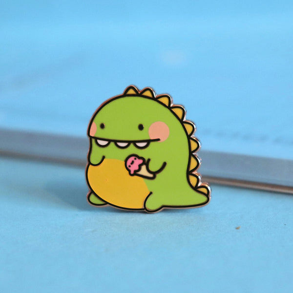 Dinosaur enamel pin on blue table