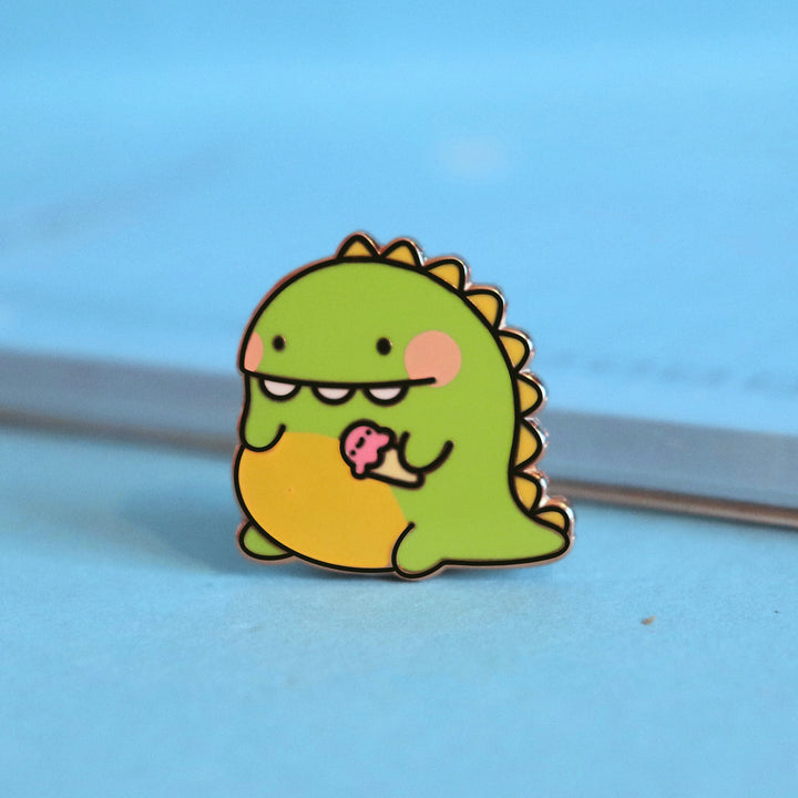 Dinosaur enamel pin on blue table