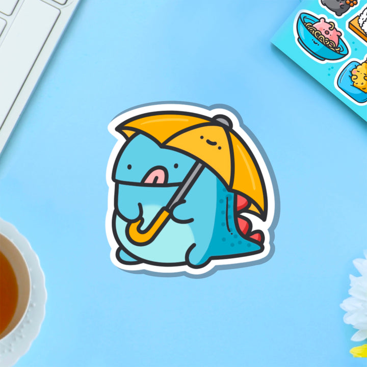 Dinosaur holding umbrella vinyl sticker on blue table