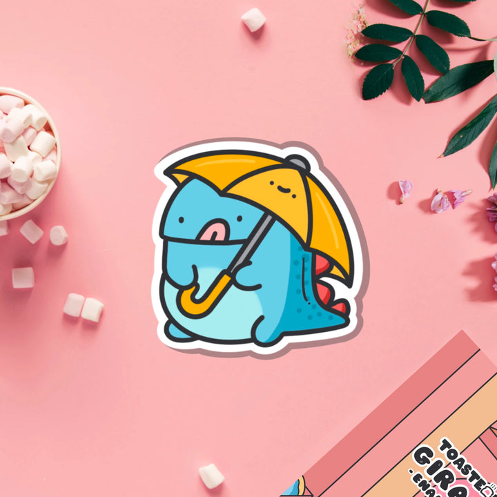 Dinosaur holding umbrella vinyl sticker on pink table