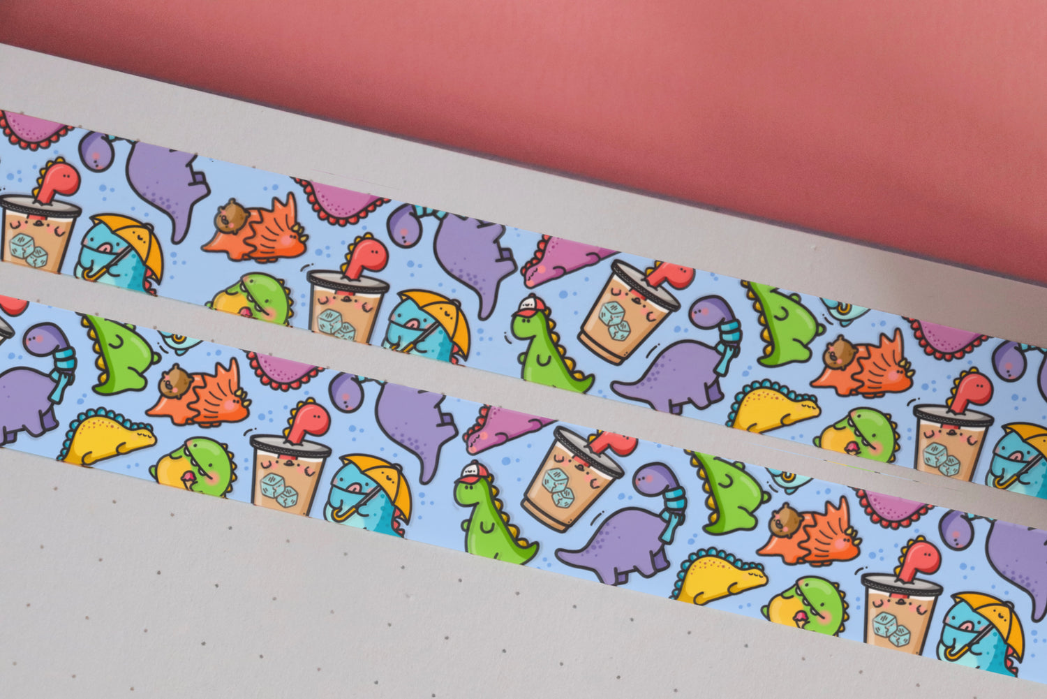 Dinosaur washi tape on pink table and notebook