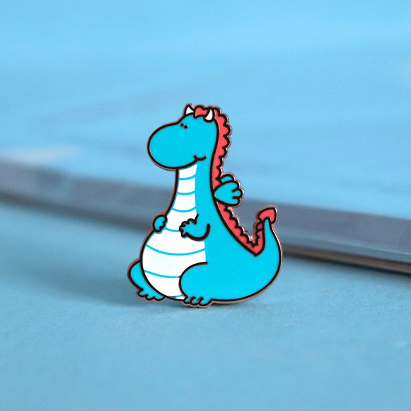 Dragon enamel pin on blue table with notepad