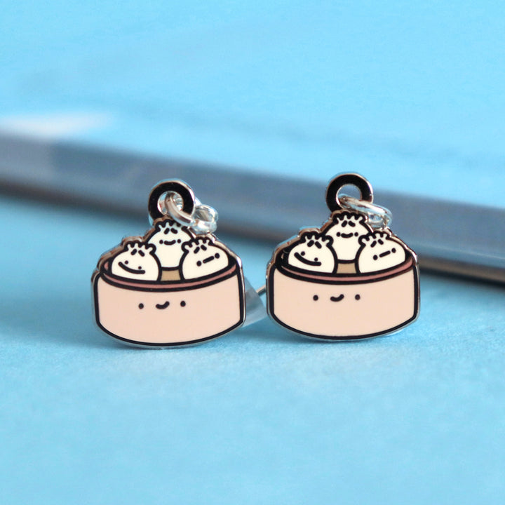 Dumpling earrings on blue table with notepad