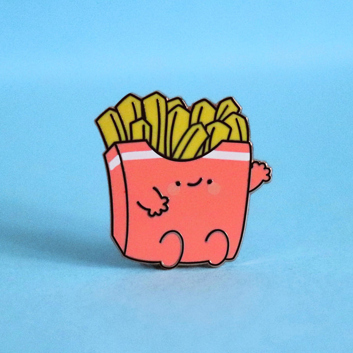 French fries enamel pin on blue desk 