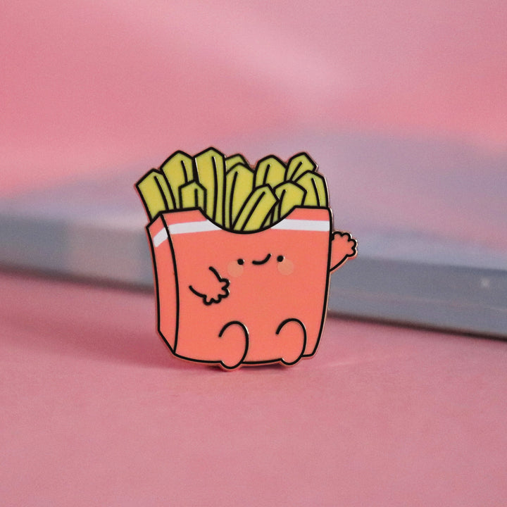 French fries enamel pin on pink table with notepad