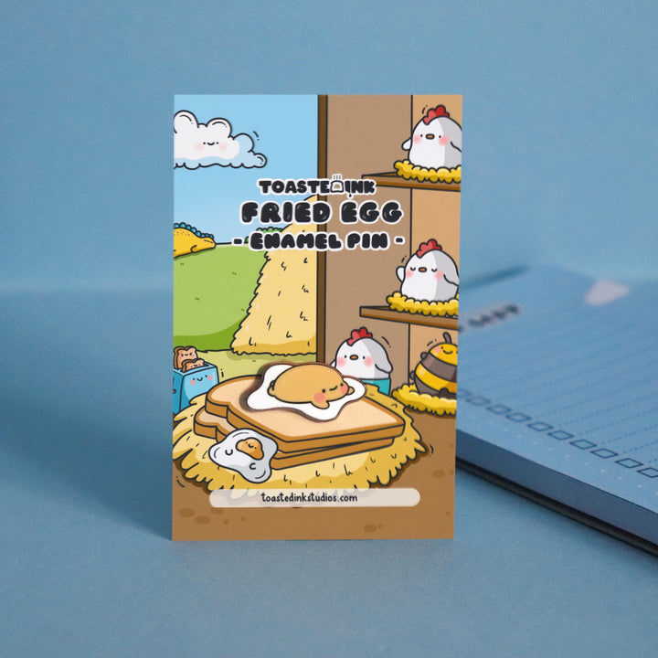 Fried egg enamel pin on backing card and blue table