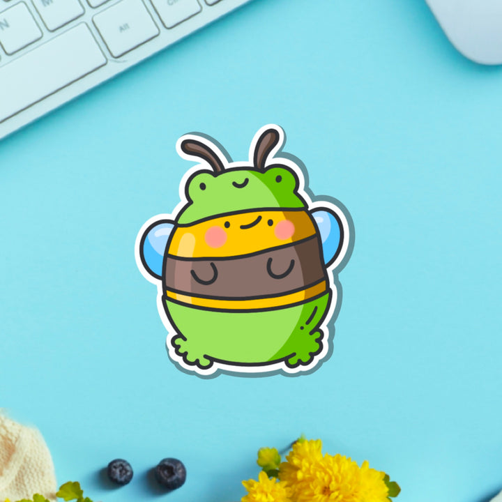 Bee dressed as frog vinyl sticker on blue table with keyboard