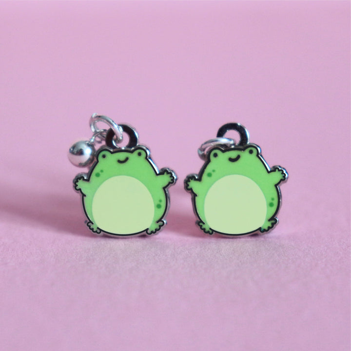 Frog stud earrings on pink table