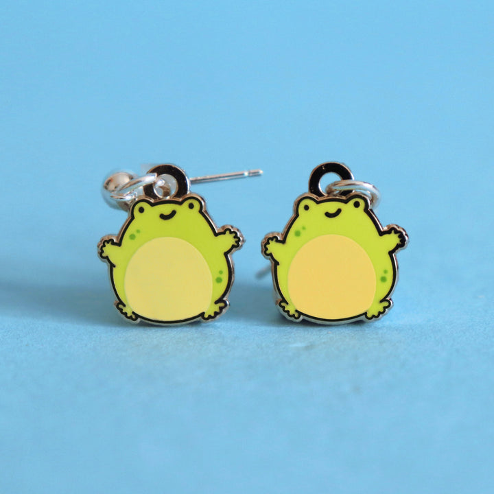 Frog stud earrings on blue table