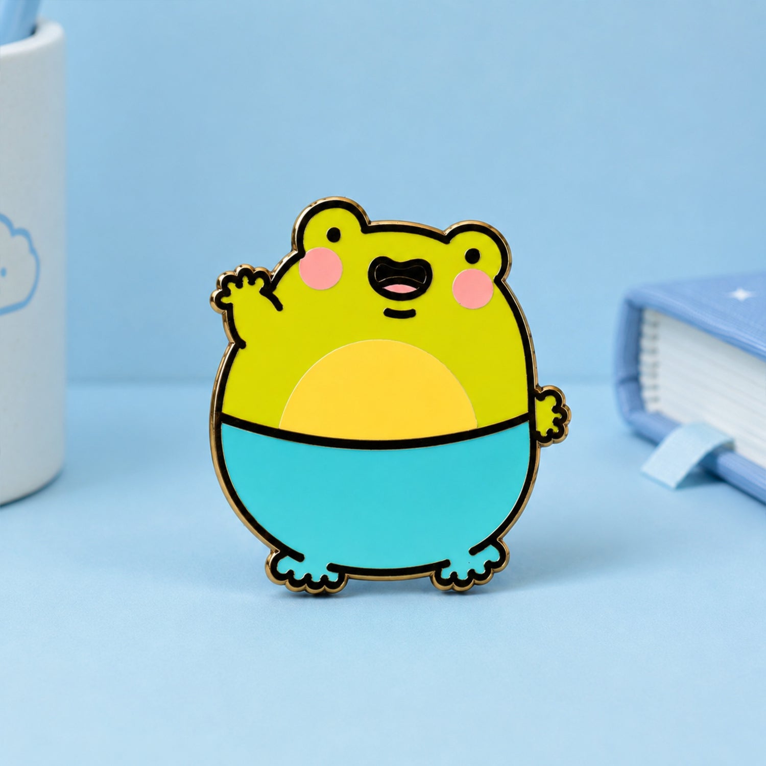 Frog Enamel Pin on blue table