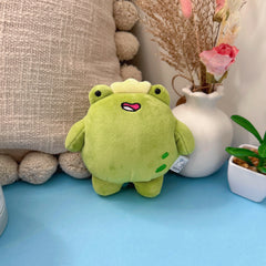 Frog keychain plush with flowers and cushion on blue table