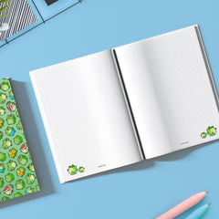 Two frogs on dot grid notebook on blue table