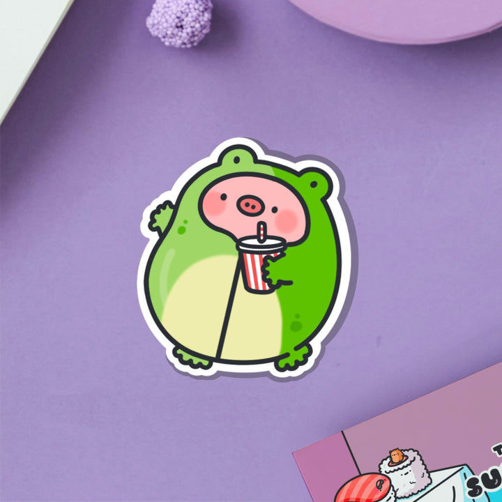 Pig in frog outfit vinyl sticker on purple table