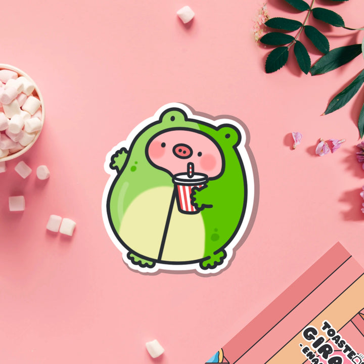 Pig in frog outfit vinyl sticker on pink table