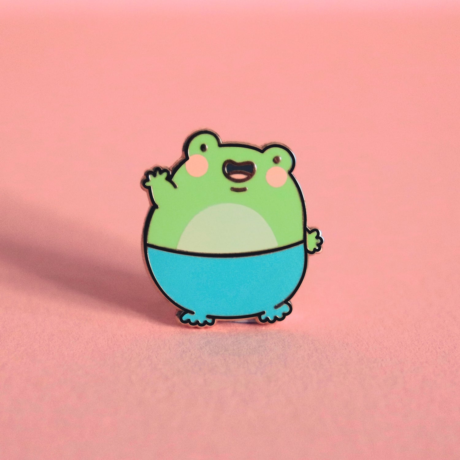 Frog enamel pin on pink table