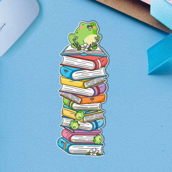 Frog sat on books bookmark on blue table