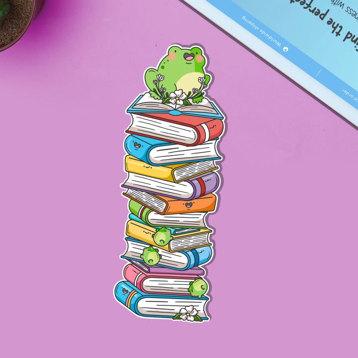 Frog sat on books bookmark on purple table