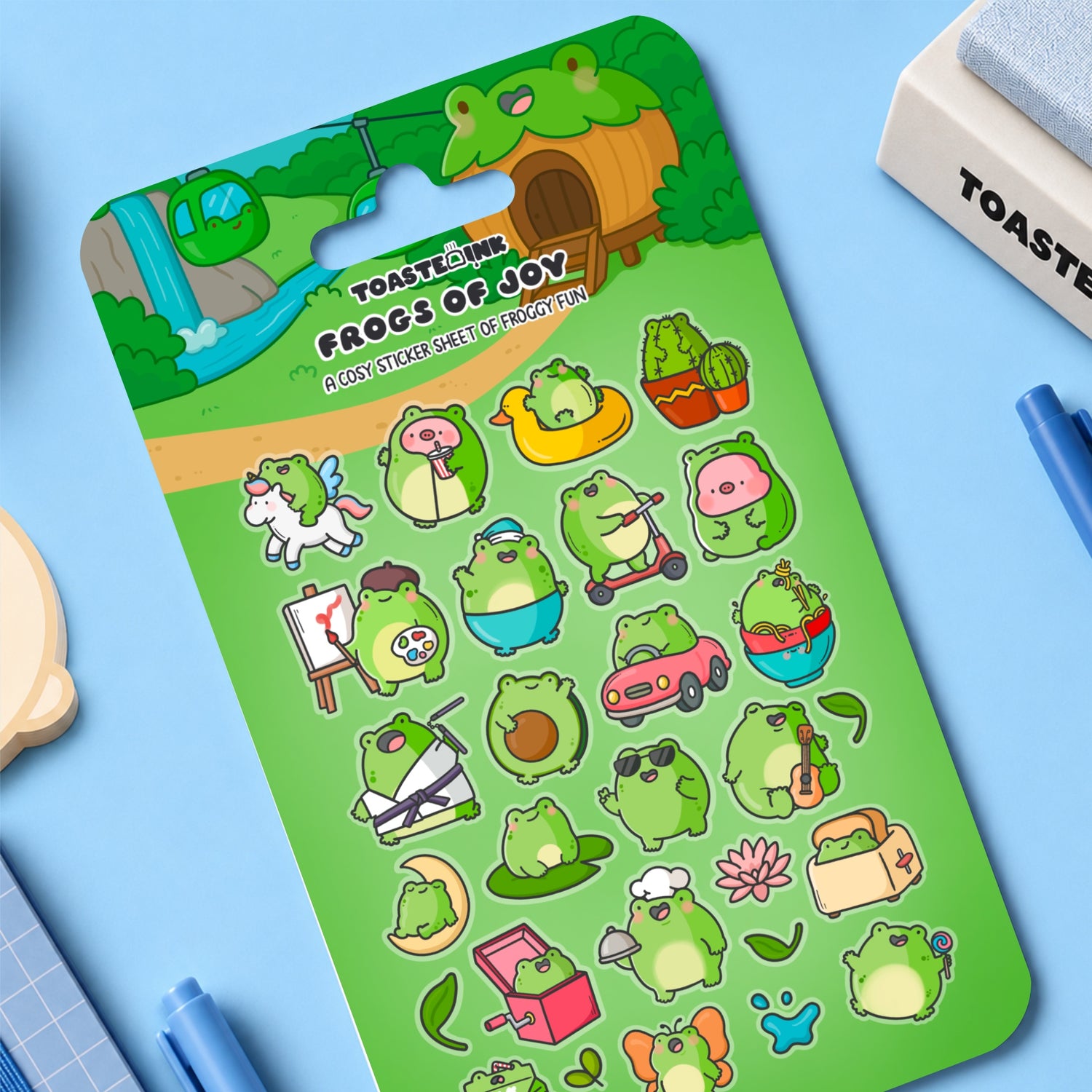 Frog sticker sheet on blue desk with notebooks and stationery