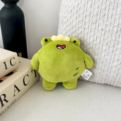 Frog Plush Keychain on beige table with books and cushion