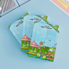 Three frog to do list notepads on blue table