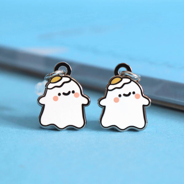 Ghost stud earrings on blue table