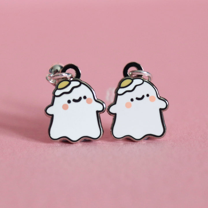 Ghost stud earrings on pink desk