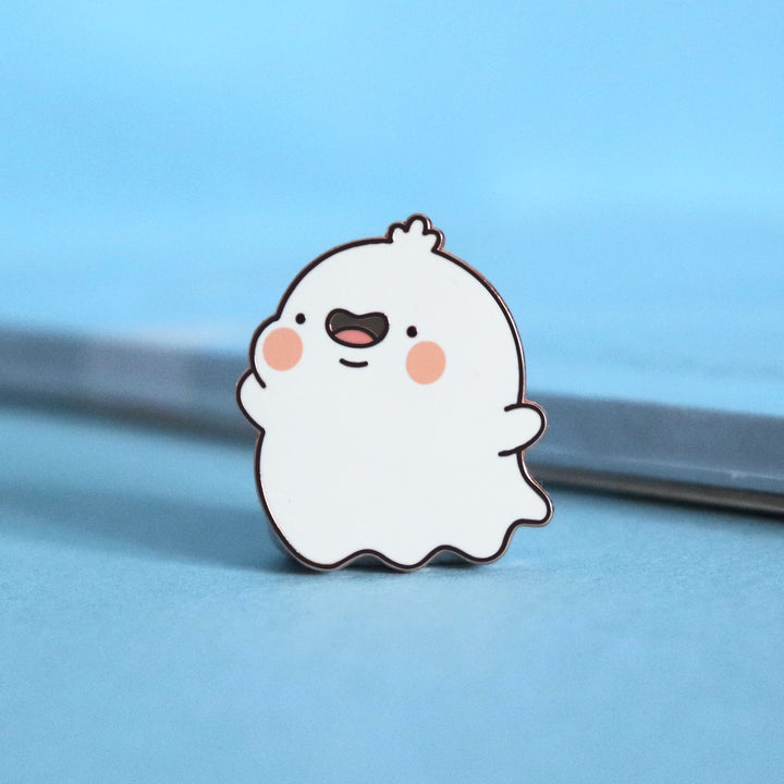Ghost enamel pin on blue desk with notepad
