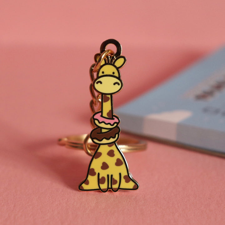 Giraffe with donuts keychain on pink table with notepad