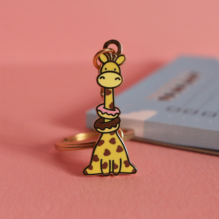 Giraffe with donuts keychain with blue notebook on pink table