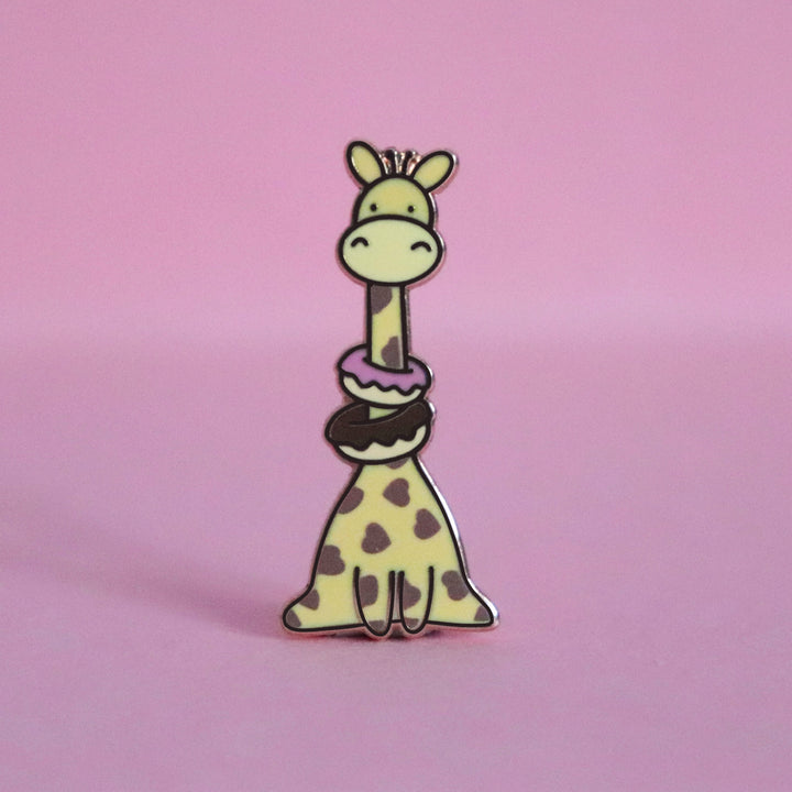 Giraffe with heart prints wearing donuts enamel pin on pink desk