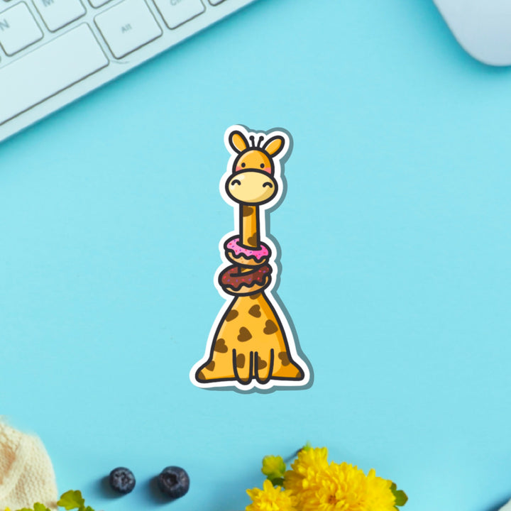 Giraffe wearing donuts vinyl sticker on blue table with keyboard