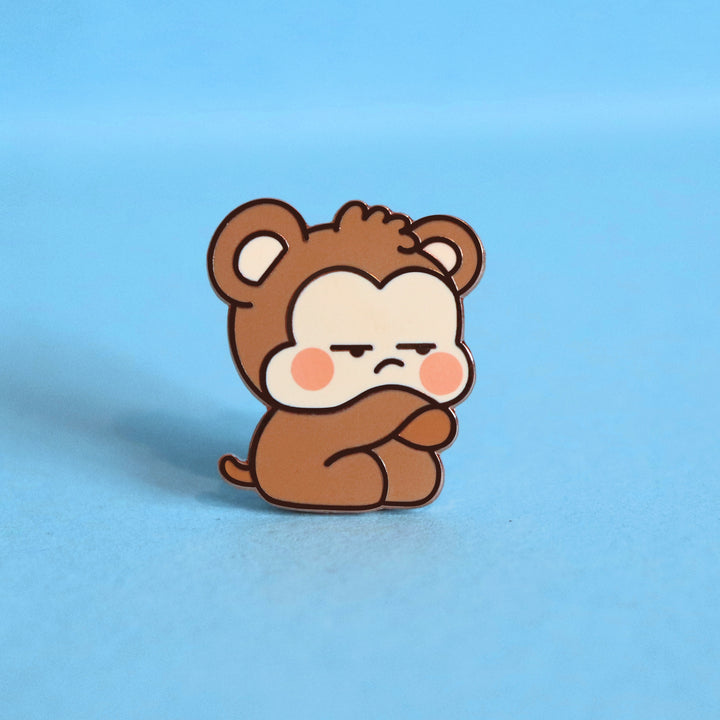 Grumpy monkey enamel pin on blue background