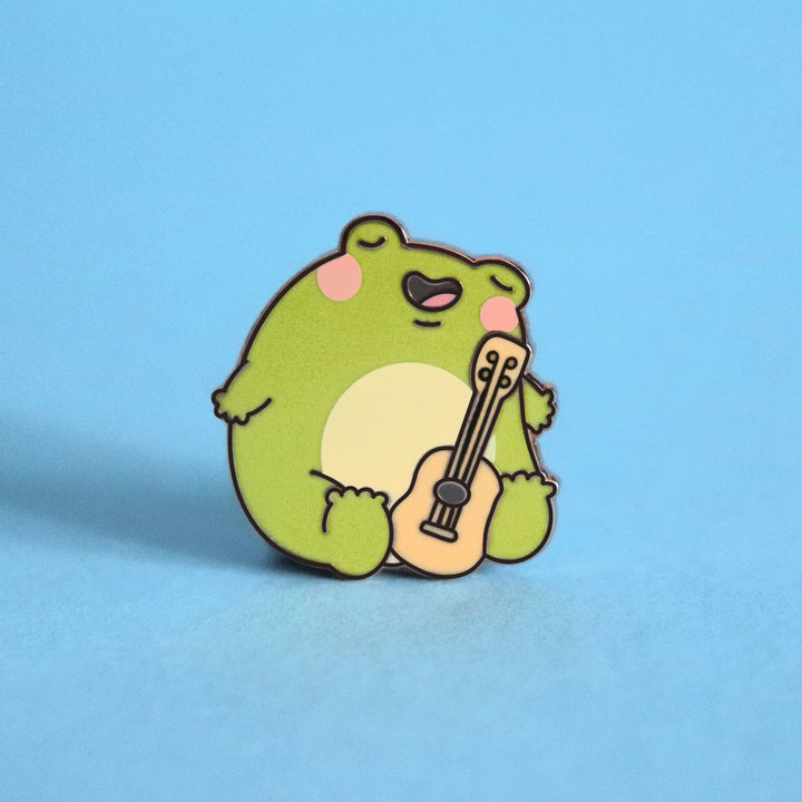 Frog with guitar enamel pin on blue background
