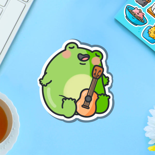 Frog playing guitar vinyl sticker on blue table