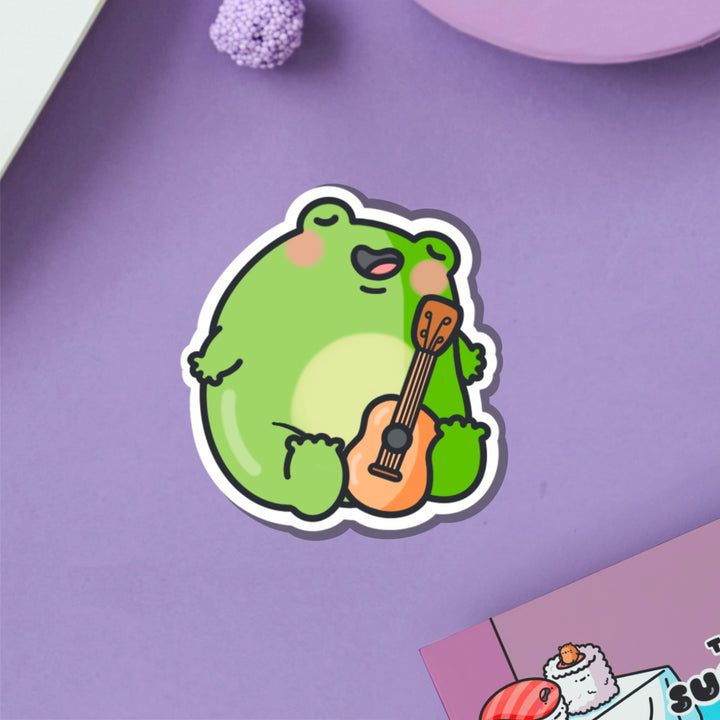 Frog playing guitar vinyl sticker on purple table