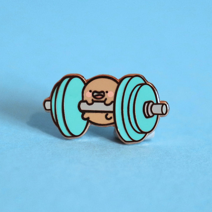 Potato lifting weights enamel pin on blue table