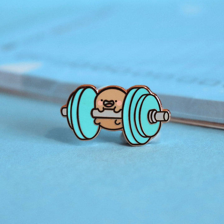 Potato lifting weights enamel pin on blue table with notepad