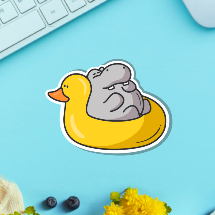 Hippo in rubber duck dinghy vinyl sticker on blue table with keyboard