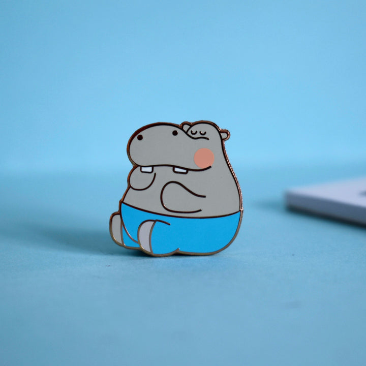 Hippo enamel pin on blue table with notepad