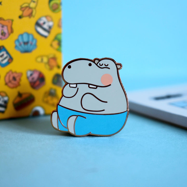 Hippo enamel pin on blue desk with notepad