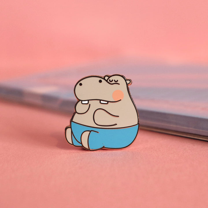 Hippo enamel pin on pink table with notepad