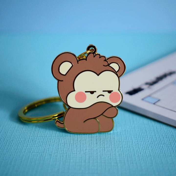 Grumpy Monkey keyring with notebook on blue table