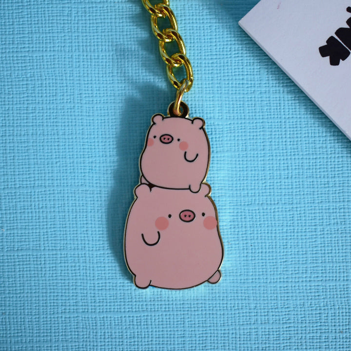 Pig keyring with gold chain on blue table