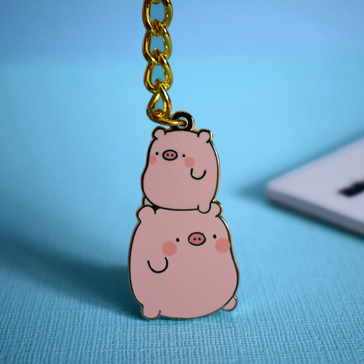 Pig keyring with gold chain and notebook on blue table