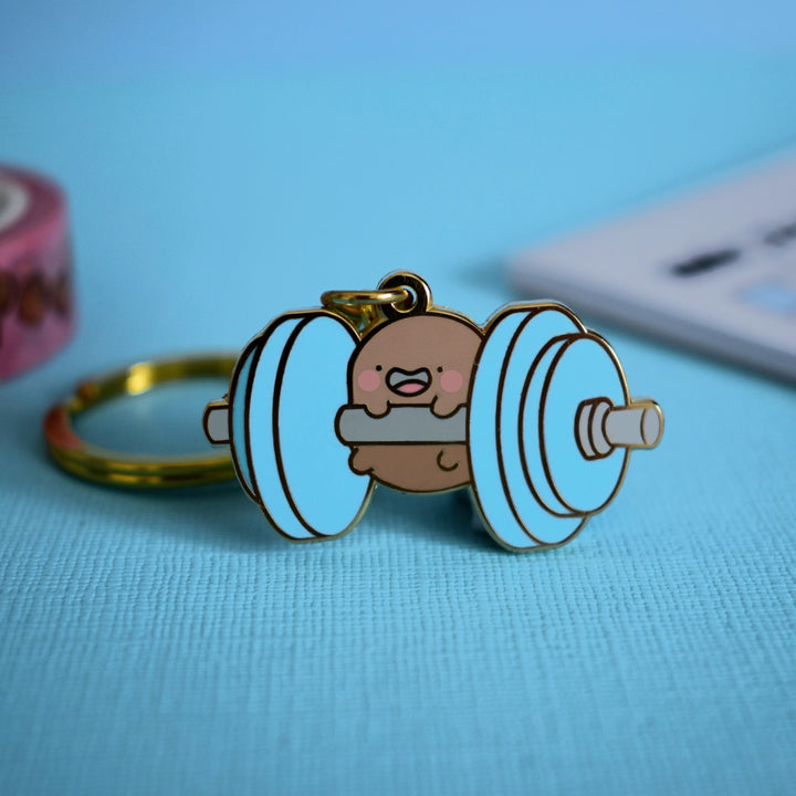 Gym potato keyring with notebook on blue table