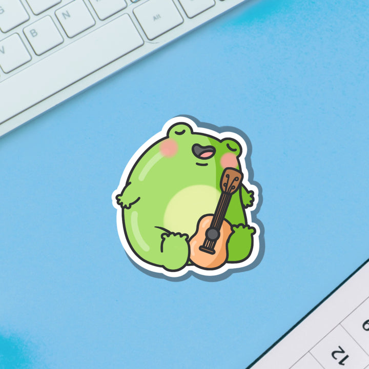 Frog playing guitar vinyl sticker on blue background 