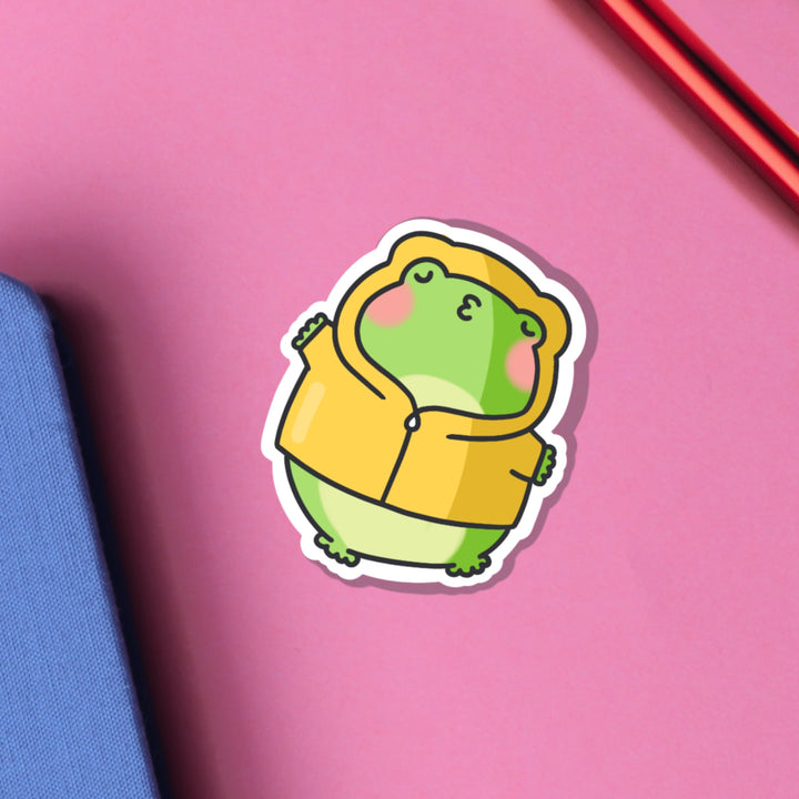 Kissing frog in hoodie vinyl sticker on pink table and notebook