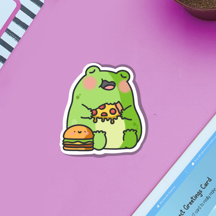 Frog eating pizza vinyl sticker on pink table with ipad