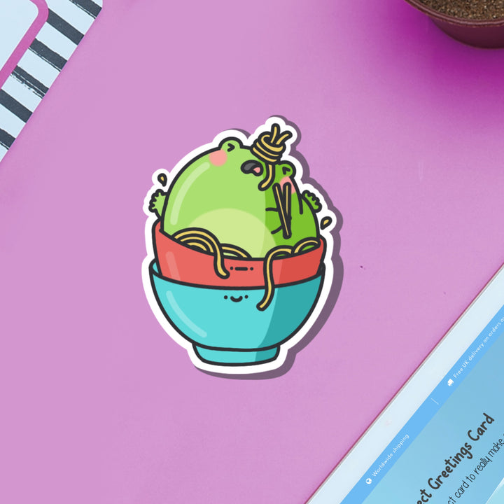 Frog stuck in noodles bowl vinyl sticker on purple table and ipad