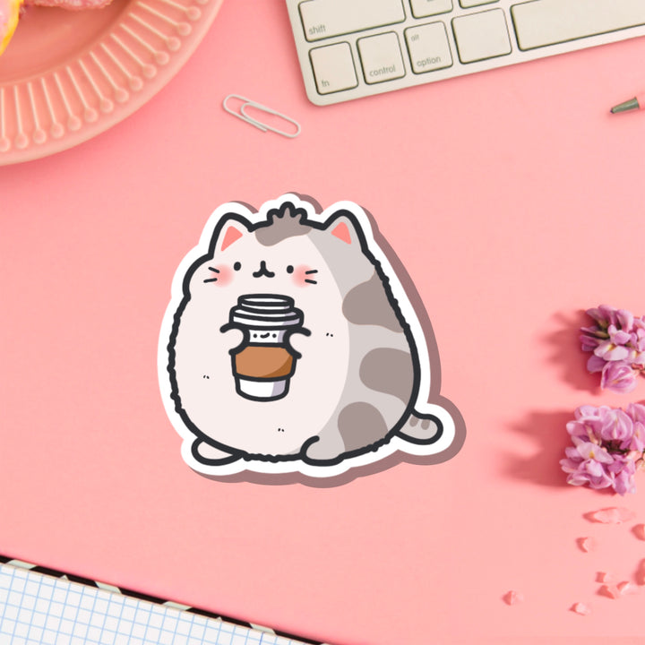 Cat holding coffee vinyl sticker on pink table
